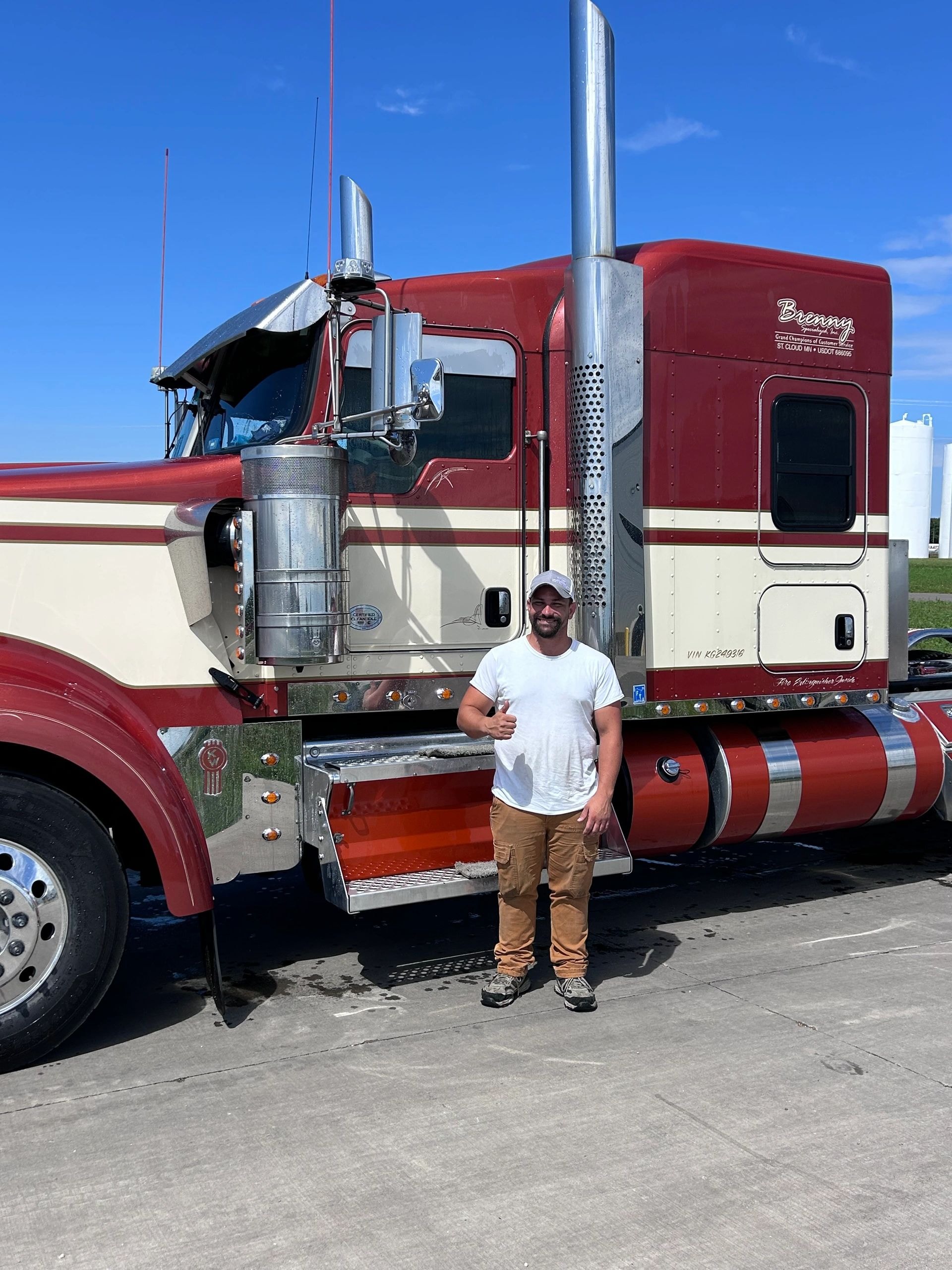 Man posing with red semi truck in service bay