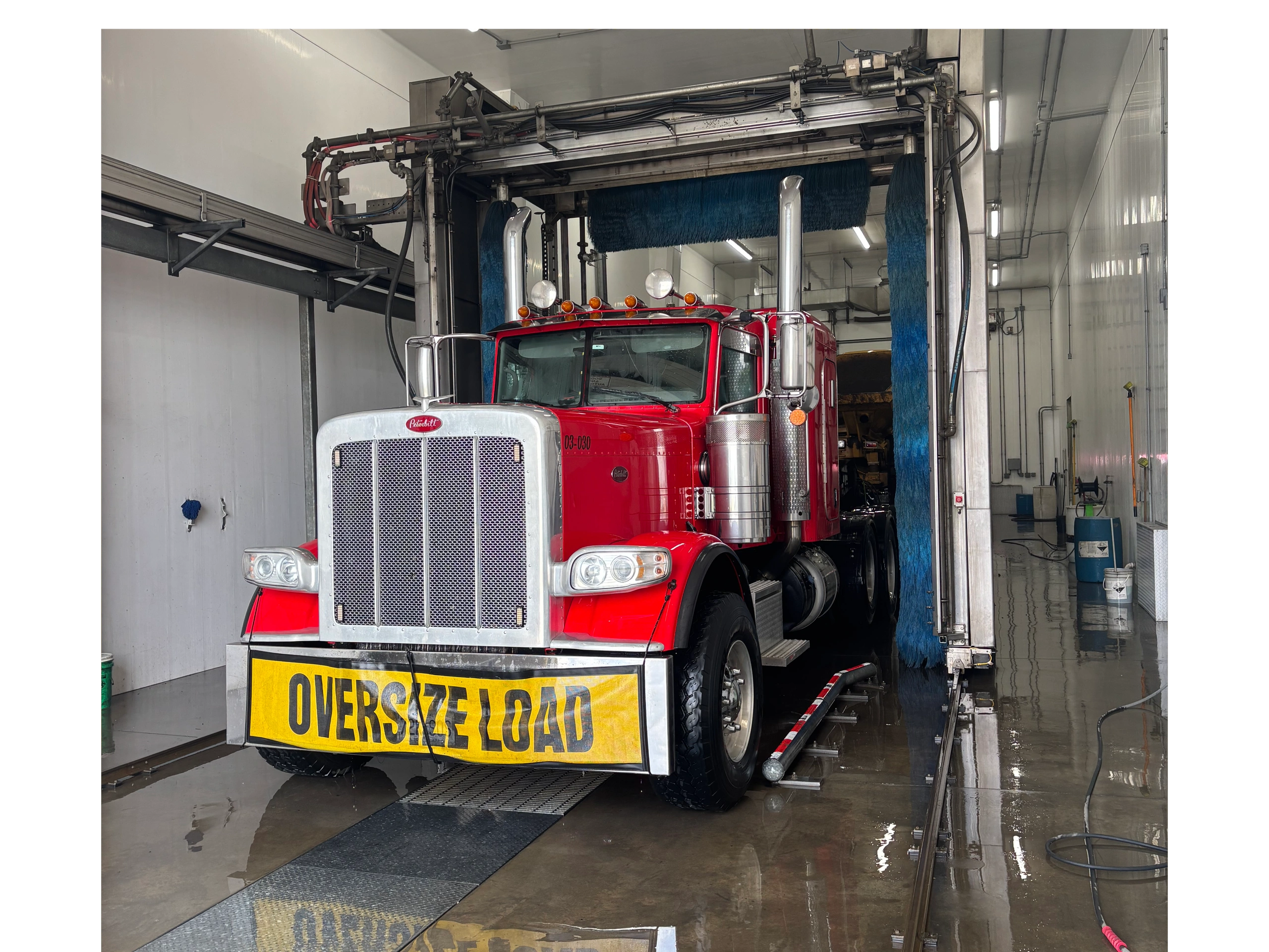 Red oversize load truck in wash bay
